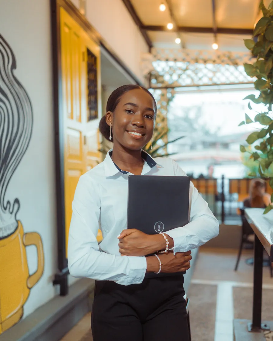 A smiling host holding a folder at a café entrance